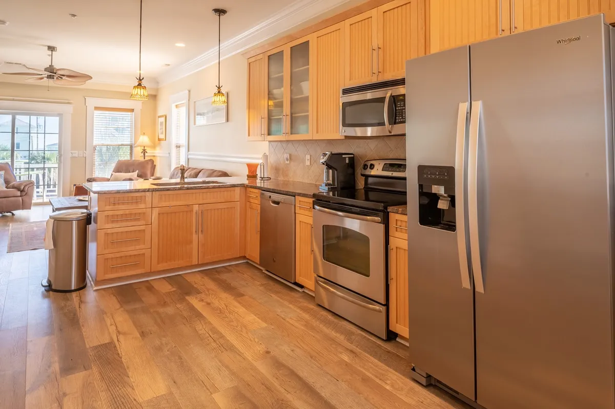 A spacious, open-concept kitchen and living area centered around a large kitchen island, stainless steel appliances, and wood cabinetry. The layout is designed for cooking, entertaining, and family gatherings, exuding a warm, welcoming atmosphere ideal for both short and long stays.