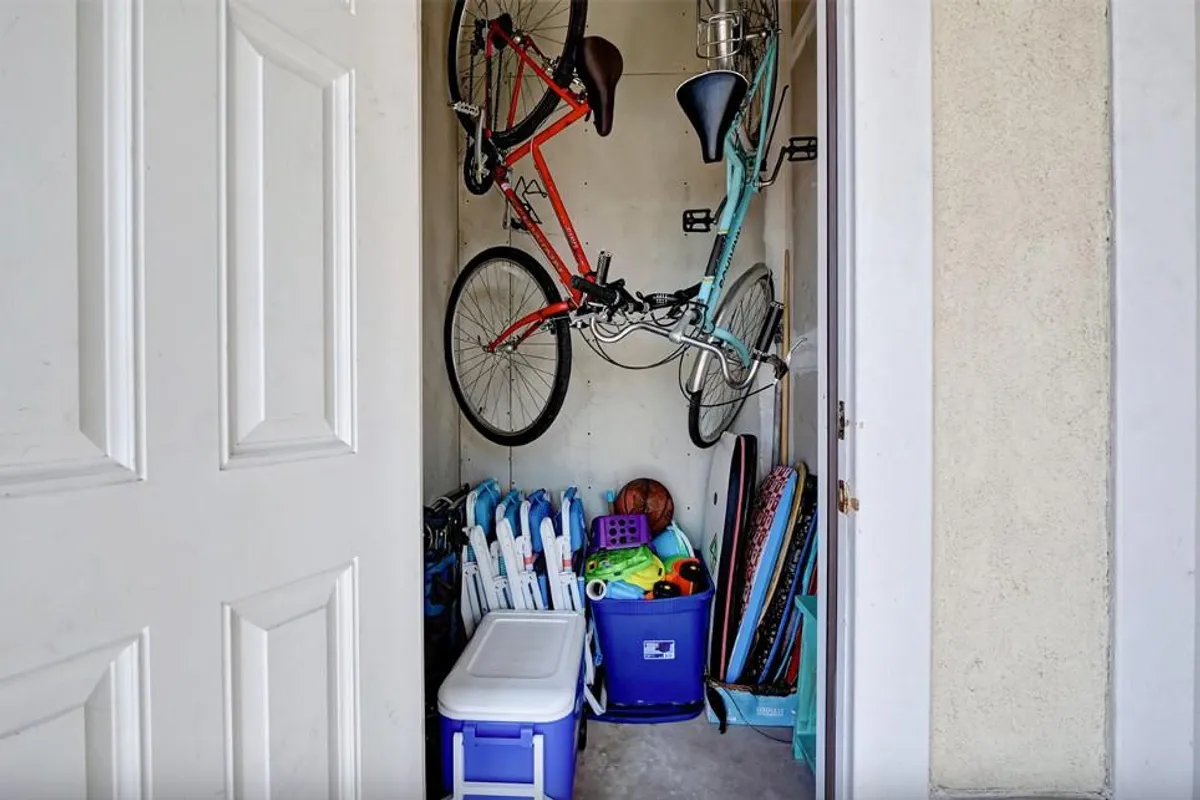 A practical storage area featuring two bicycles, storage containers, a cooler, and various sports equipment. The space is organized and clearly designed for easy access to adventure gear.