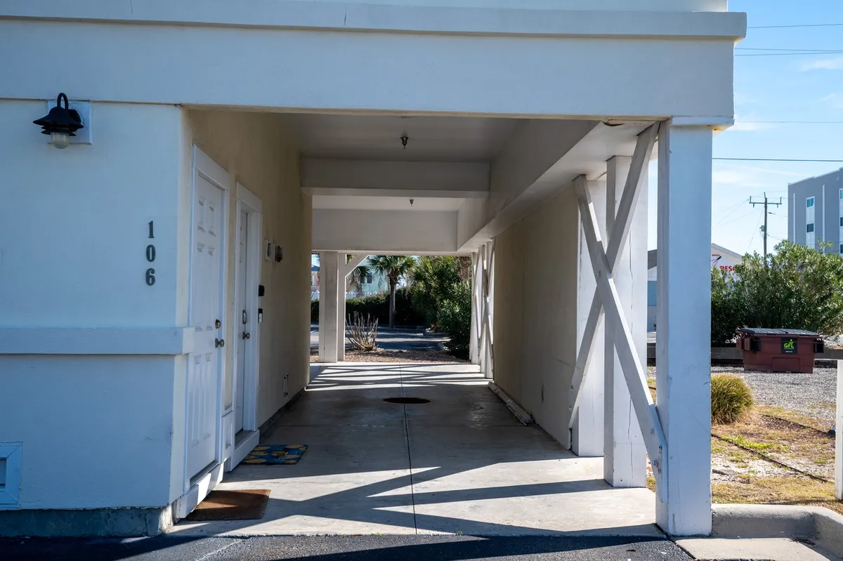 An exterior view focusing on the property's front doors and covered walkway, with a decorative mat welcoming guests. The scene conveys moments of arrival and departure, reinforcing the property's accessibility.
