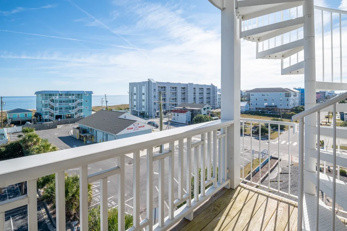 An exterior shot featuring a balcony with a spiral staircase leading up, an expansive sea view in the background, and stylish railings. The mood is serene, inviting viewers to imagine enjoying coffee in the morning or sunset gatherings at dusk.